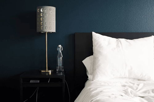 Bed and bedside table with a lamp and water bottle in a hotel room