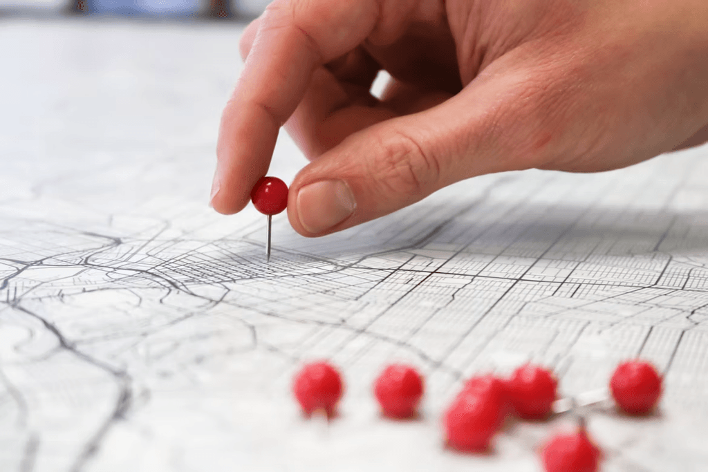 Person placing red location marker pins on a map