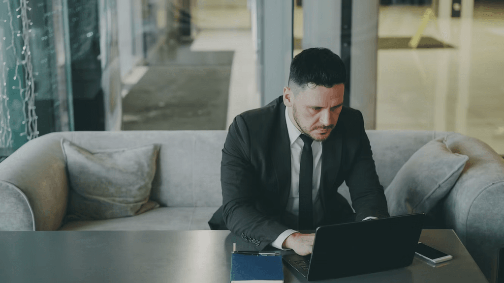 Man sat at a table working on his laptop looking focussed 